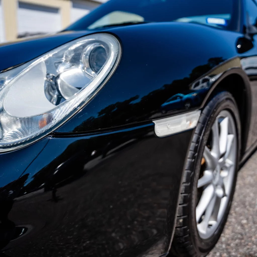 A close-up of the ceramic coating on a sleek black sports car, showcasing its elegant design and powerful presence.