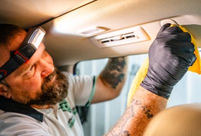 Brian, owner of Summer Breeze Ceramic Coating & Mobile Detailing, wears a headlamp while performing a full interior detail, focusing on the visor.