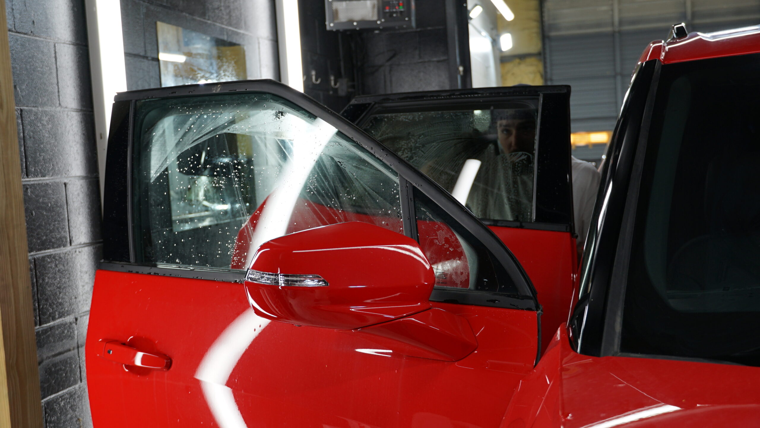 A red car getting window tinting in the Summer Breeze garage.