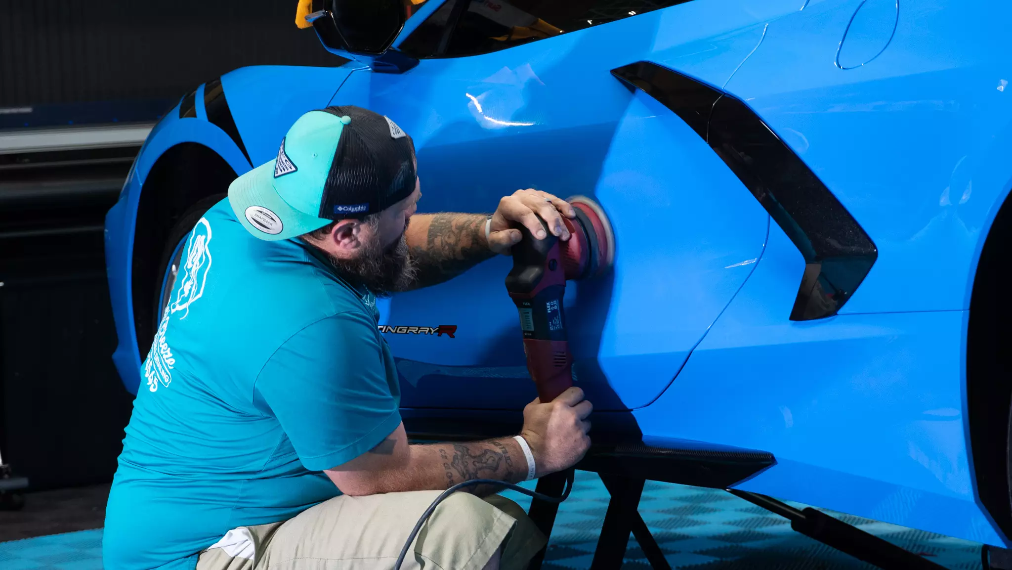 Owner of Summer Breeze Ceramic Coating & Mobile Detailing, Brian, buffering the exterior of a blue corvette