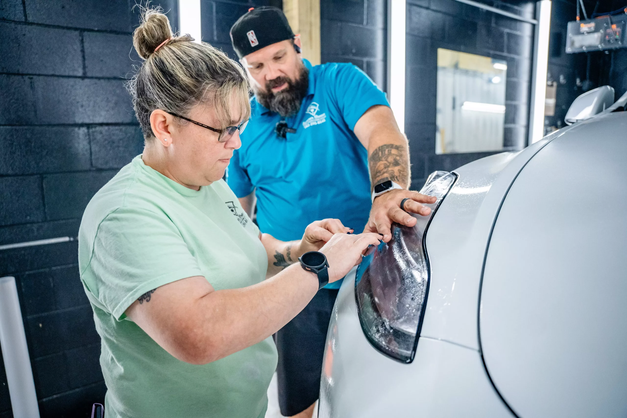 Brian Gitzen and Amber Gitzen professionally installing PPF on a white Tesla | Summer Breeze Ceramic Coating & Mobile Detailing | South Carolina